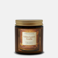 A jar candle labeled 'Fallen Leaves Feuille' by Candle Elegance, in an amber glass container with a gold metal lid, shown on a light gray background.