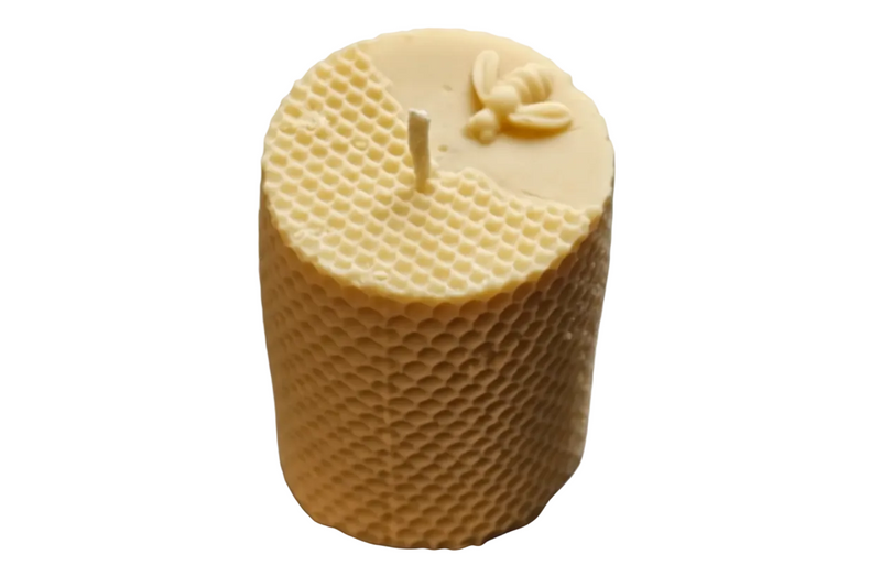 "Bee Pillar Organic Beeswax Candle with honeycomb design".  A beige pillar candle with a honeycomb texture and a bee motif on the top