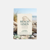 Beach Linen Candle Elegance diffuser refill in a cream-colored paper sleeve featuring a beach scene with driftwood, seashells, and ocean waves, set against a light gray background.
