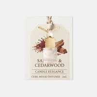A 2ml cube mood diffuser from Candle Elegance, featuring a small clear cube filled with wax and a light wood diffuser core, attached to a cream-colored hanging tag with illustrations of saffron and cedarwood.