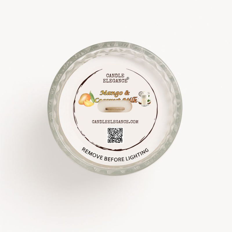 Top-down view of a Candle Elegance dusto cover, 'Mango & Coconut Butter' scented candle in a clear textured glass jar, showing the white wax surface and printed label.