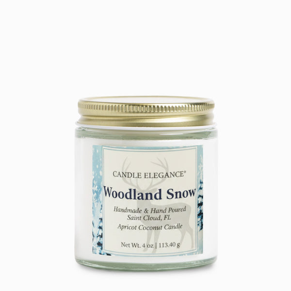 A 4 oz glass jar candle with a gold metal lid and a white label reading 'Woodland Snow' by Candle Elegance, shown on a clean white background.