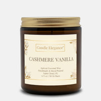A Candle Elegance Cashmere Vanilla scented candle in an amber glass jar with a gold metal lid and a cream-colored label, set against a light gray background.