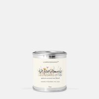 A 8 oz candle in a silver metal tin with a cream-colored label. The label features the brand name 'Candle Elegance' and the scent name 'Wild Flower' with a delicate floral illustration.