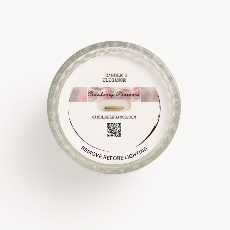 Top-down dust cover view of a Candle Elegance Cranberry Pearsson candle in a clear glass container with a white wax surface and a white paper label.