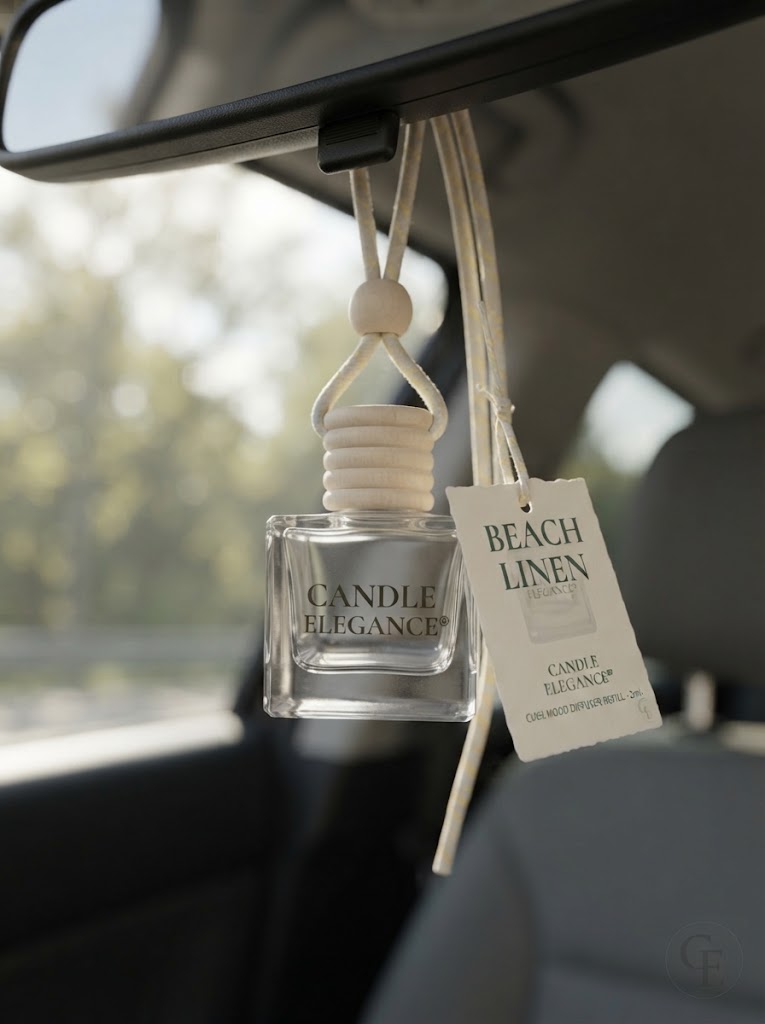 A clear glass car air freshener bottle labeled 'CANDLE ELEGANCE' hanging from a car rearview mirror, with a cream-colored reed diffuser top and a hanging tag that reads 'BEACH LINEN'.