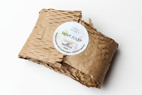 Beeswax melt in brown paper packaging with a label on a beige background
