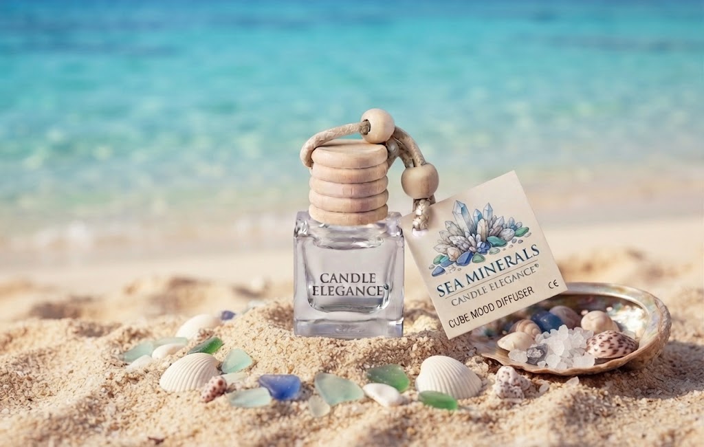 Sea Minerals Cube Mood Diffuser by Candle Elegance featuring a clear glass bottle with a wooden lid, wooden cord, and a labeled retail card, displayed on a sandy beach setting with seashells and sea glass.