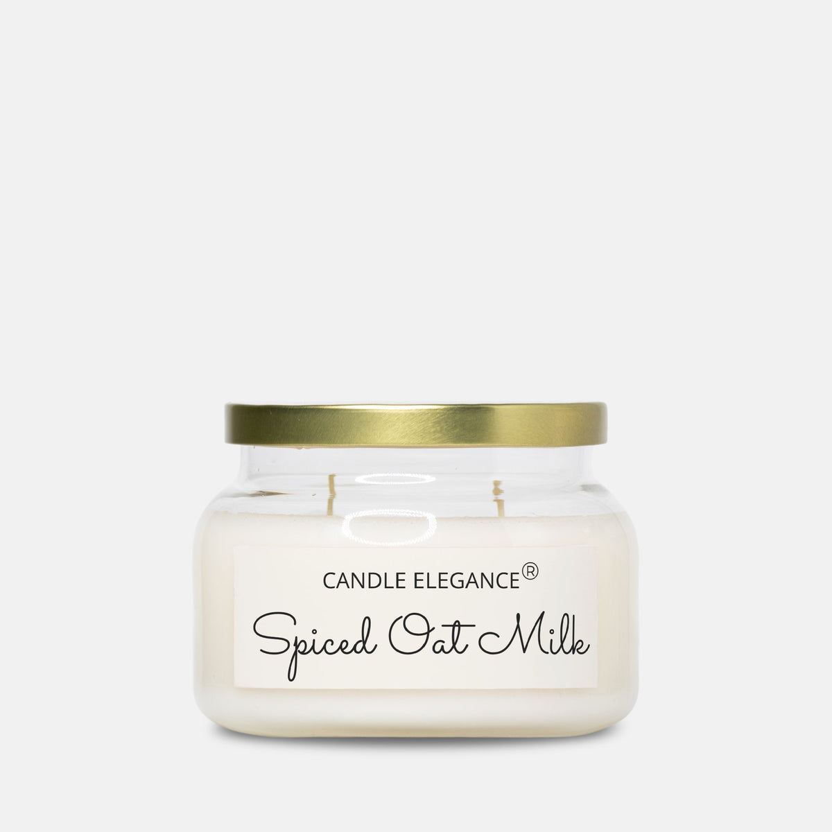 A Candle Elegance 'Spiced Oat Milk' scented candle in a clear glass jar with a gold metal lid and a white label, set against a solid light gray background.