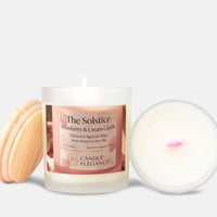 A lit white glass jar candle labeled 'The Solstice Strawberry & Cream Candle' by Candle Elegance, shown with a light wood lid on the left and the open lid with white wax on the right against a light gray background.