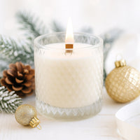 Candle in a glass holder with Christmas decorations on a white surface