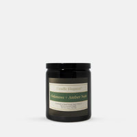 A black glass jar candle with a black lid and a cream label reading 'Candle Elegance' and 'Oakmoss + Amber Noir', photographed on a clean white background.