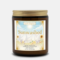 A 6.9 oz amber glass jar candle with a gold lid and a decorative label reading 'Sunwashed' by Candle Elegance, set against a light gray background.