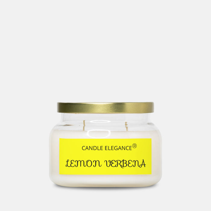 A Candle Elegance 'Lemon Verbena' scented candle in a clear glass jar with a gold metal lid and a bright yellow label, set against a plain light gray background.