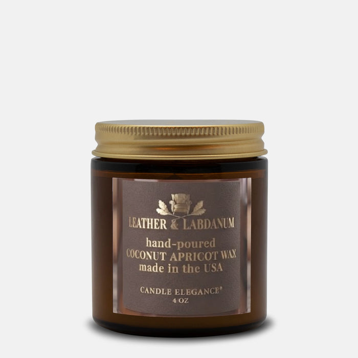 A 4 oz amber glass jar candle with a gold metal lid and a brown label reading 'Leather & Labdanum' and 'Coconut Apricot Wax'.