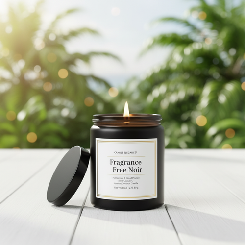 A lit candle in a dark amber glass jar sits on a white wooden surface with its black lid leaning beside it. The background is a softly blurred outdoor scene with green foliage and warm bokeh lights.