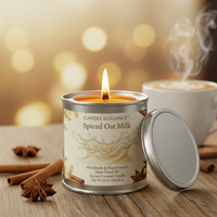 A lit candle in a silver tin labeled 'Candle Elegance Spiced Oat Milk' sits on a wooden surface with cinnamon sticks and star anise, while a steaming mug appears blurred in the background against warm bokeh lights.