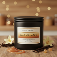 A black candle jar labeled 'Candle Elegance Vanilla Bean Noir' sits on a wooden surface with vanilla flowers, vanilla beans, and caramel drizzle around it, against a warm blurred background with bokeh lights.