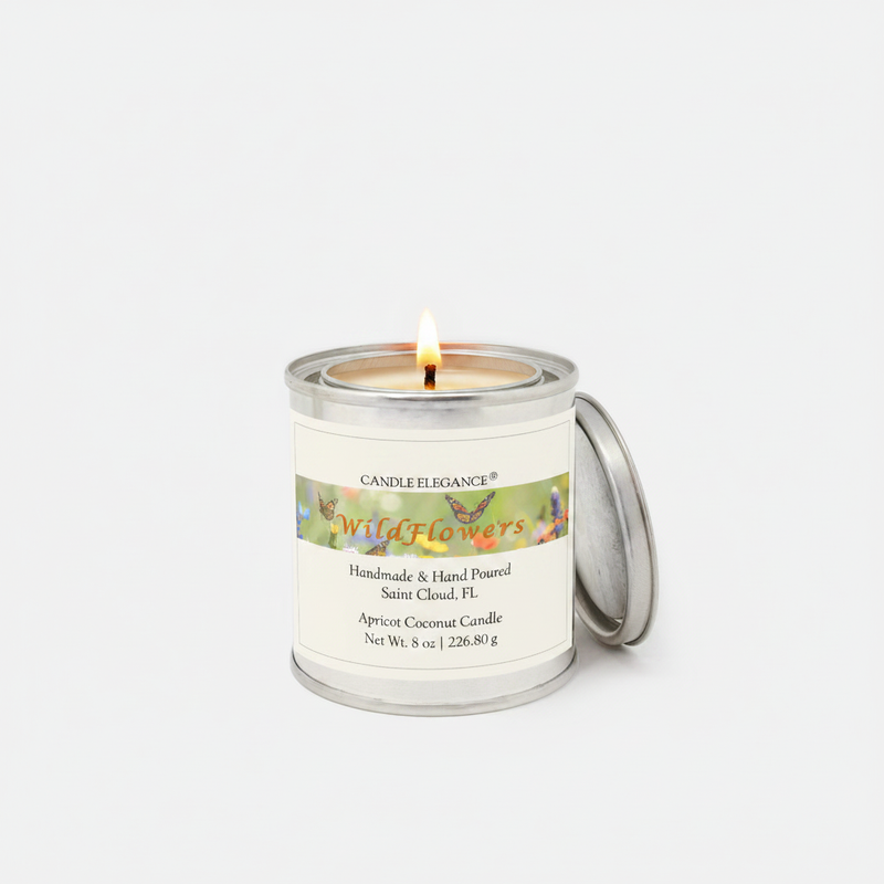 A lit Candle Elegance 'Wildflowers' apricot coconut candle in a silver metal tin with its lid resting beside it, set against a clean white background.